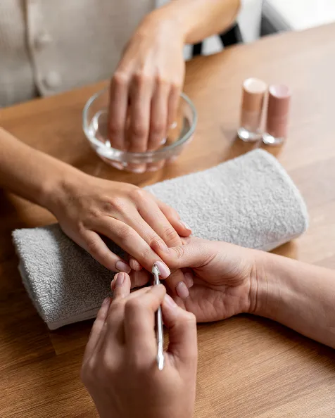 Une manucure en cours, une personne appliquant du vernis à ongles sur une autre main.