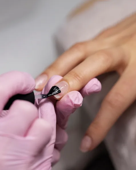 Une manucure en cours, une personne appliquant du vernis à ongles sur une autre main.