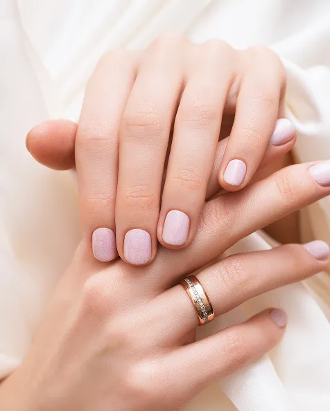 Deux mains féminines avec des ongles manucurés en rose pâle.
