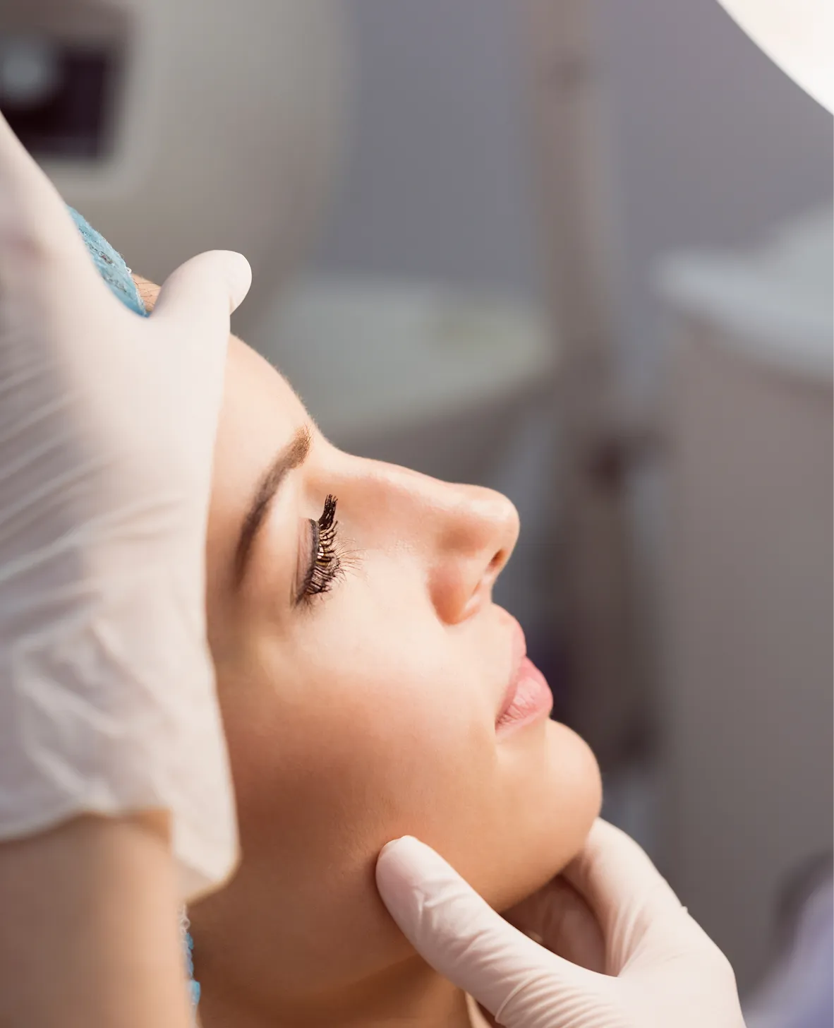 Une personne recevant un soin esthétique sur le visage, avec des mains gantées appliquant un produit.
